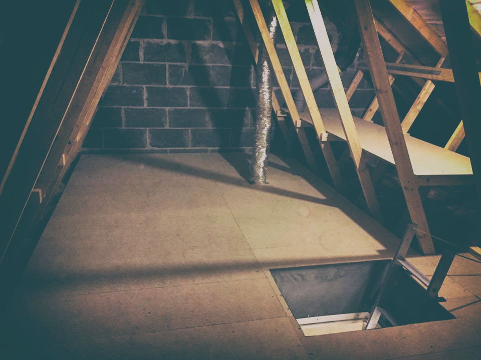 dark loft boarded attic with metal ladder